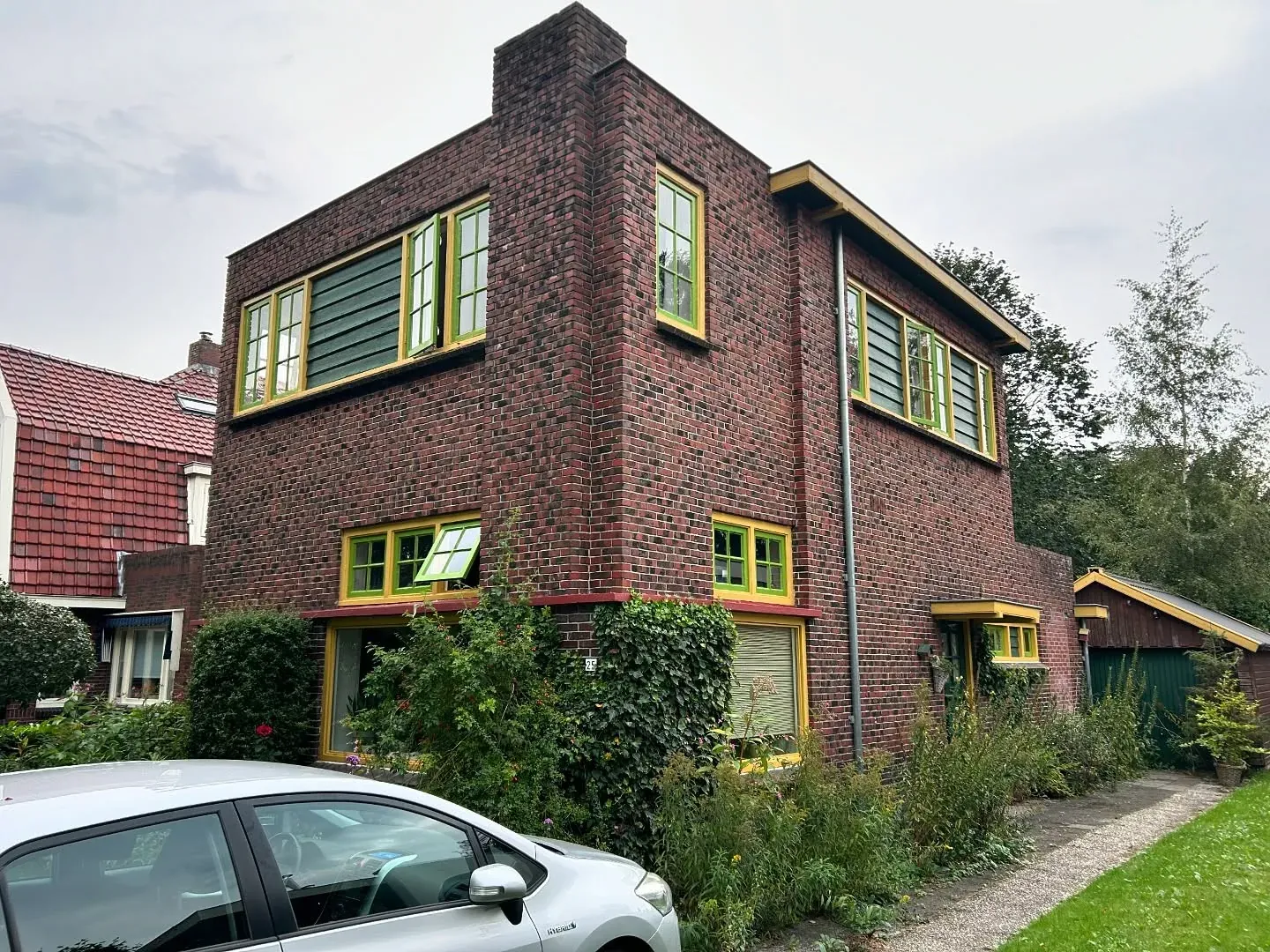 Bakstenen hoekpand met gele en groene kozijnen in de stijl van de Amsterdamse School