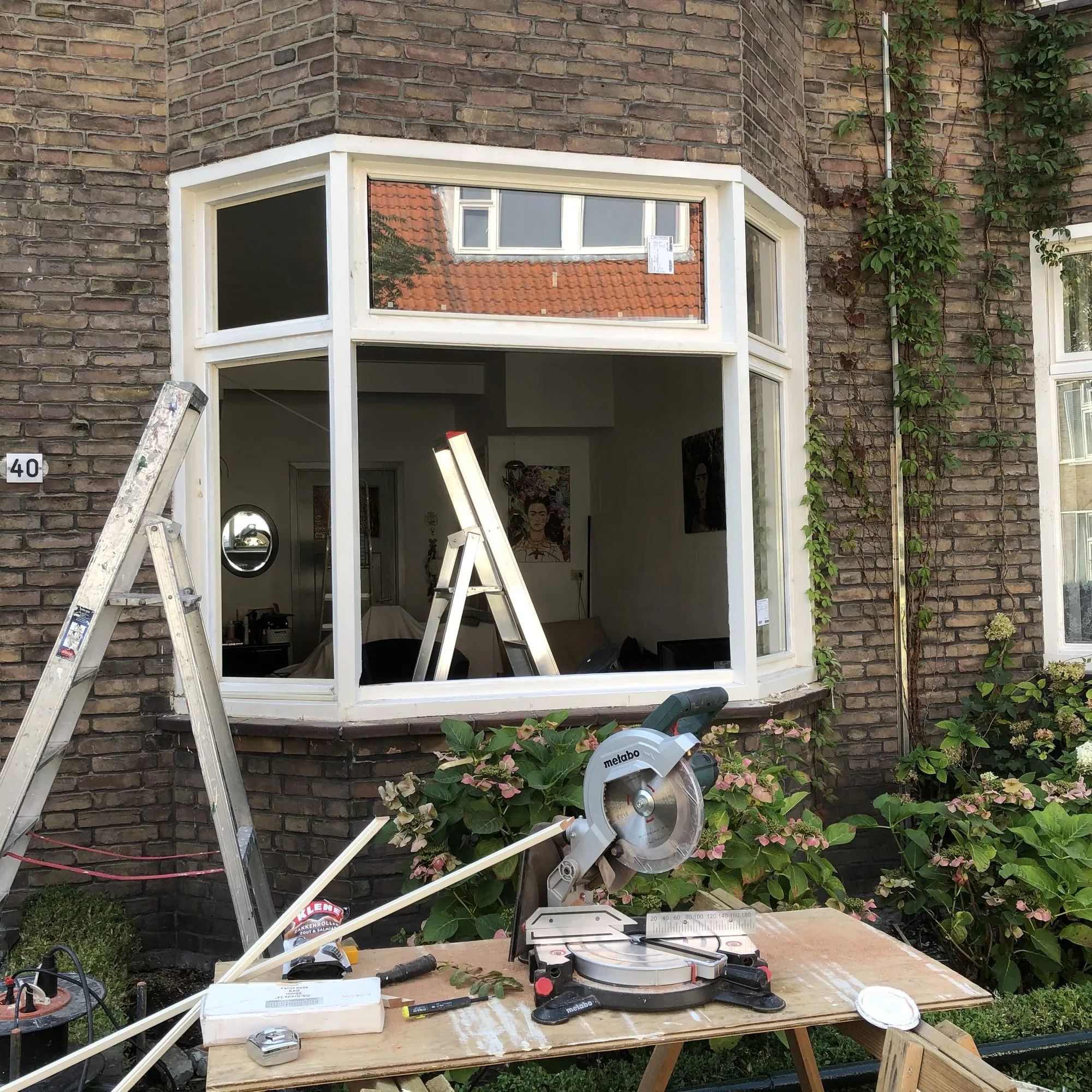 Een houten raamkozijn op de werkbank, met gereedschap en nieuwe glaslatten ernaast
