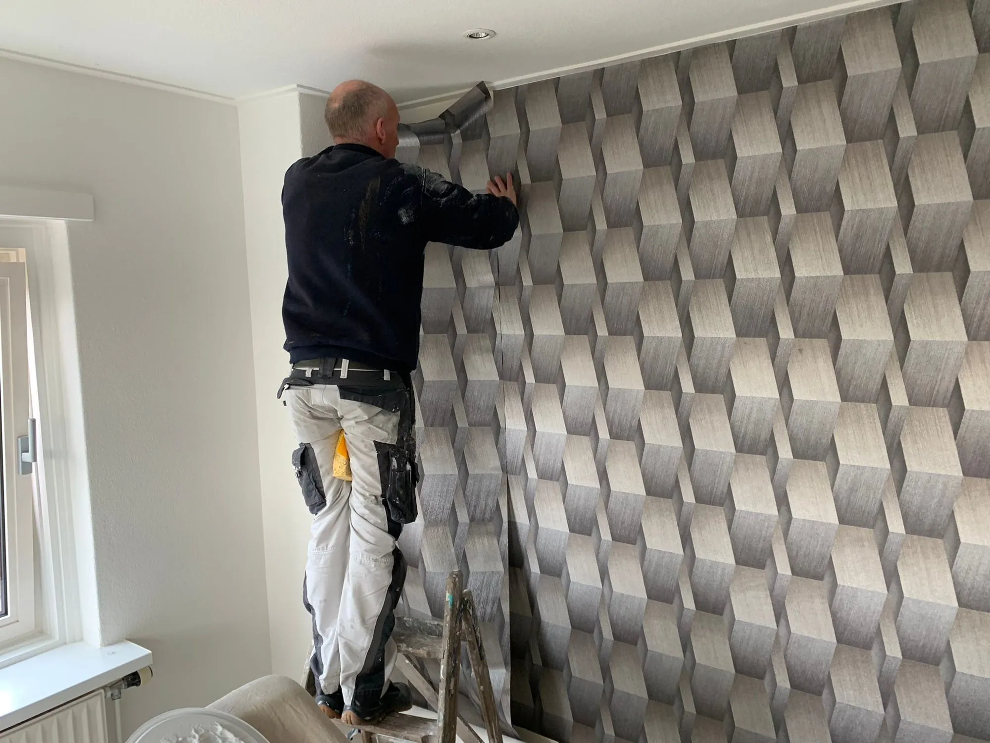 Behanger die een baan behang met patroon gladstrijkt