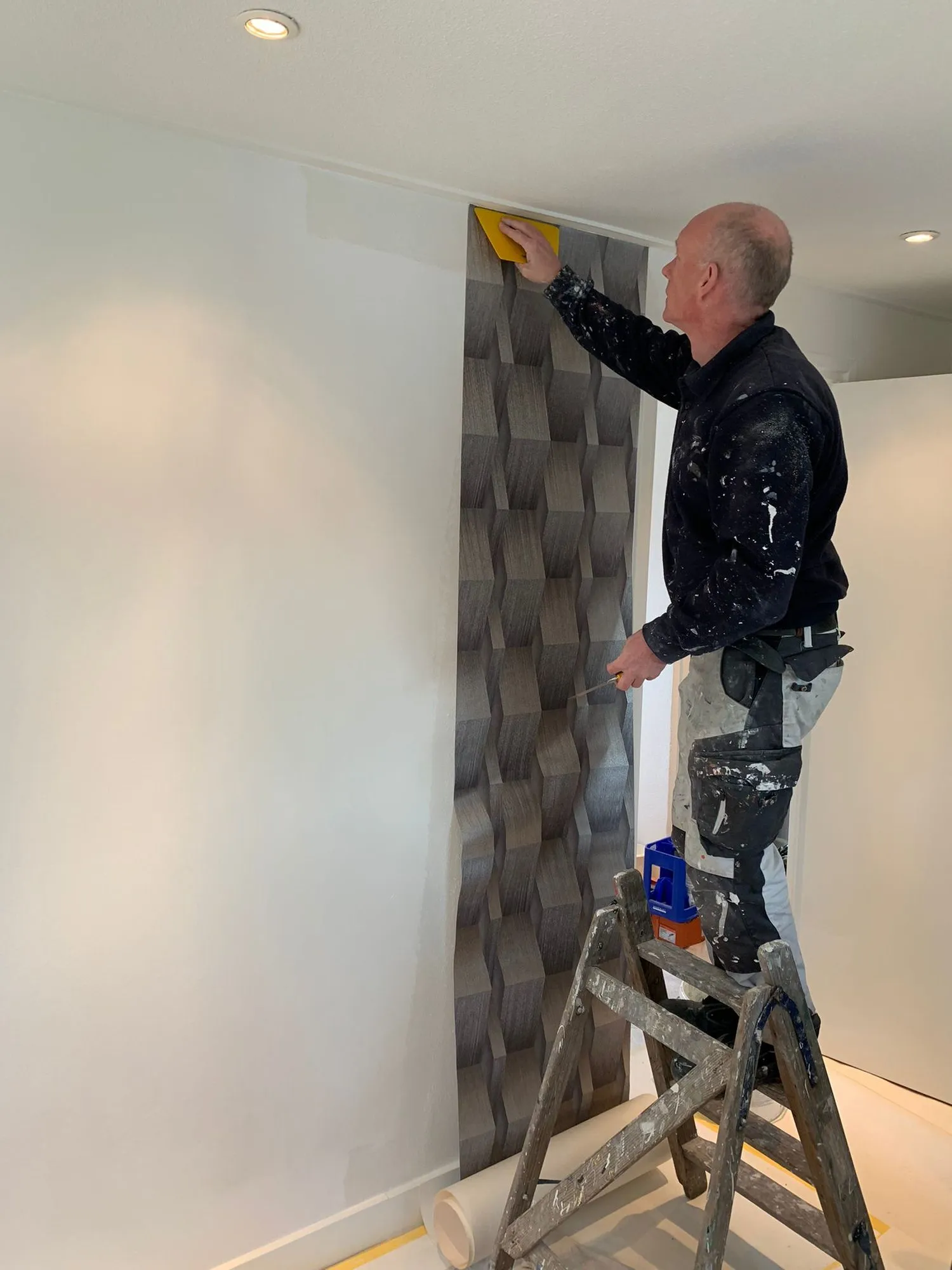 Behanger op een trap die een baan behang aanbrengt