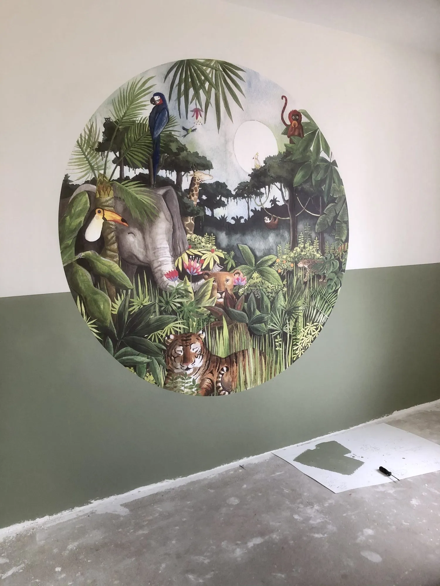 Rond fotobehang met een jungletafereel op een wand boven een groene lambrisering