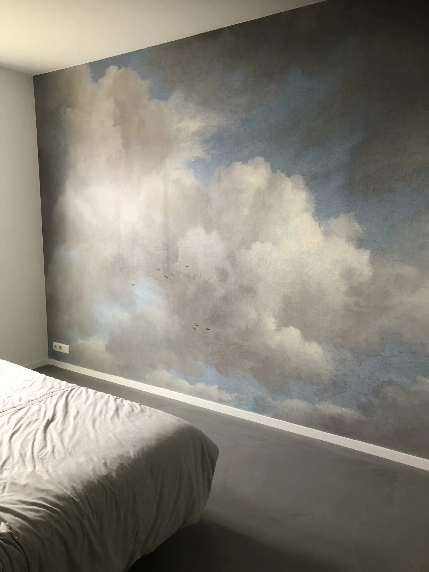 Wand met een wolkenluchtbehang in een slaapkamer