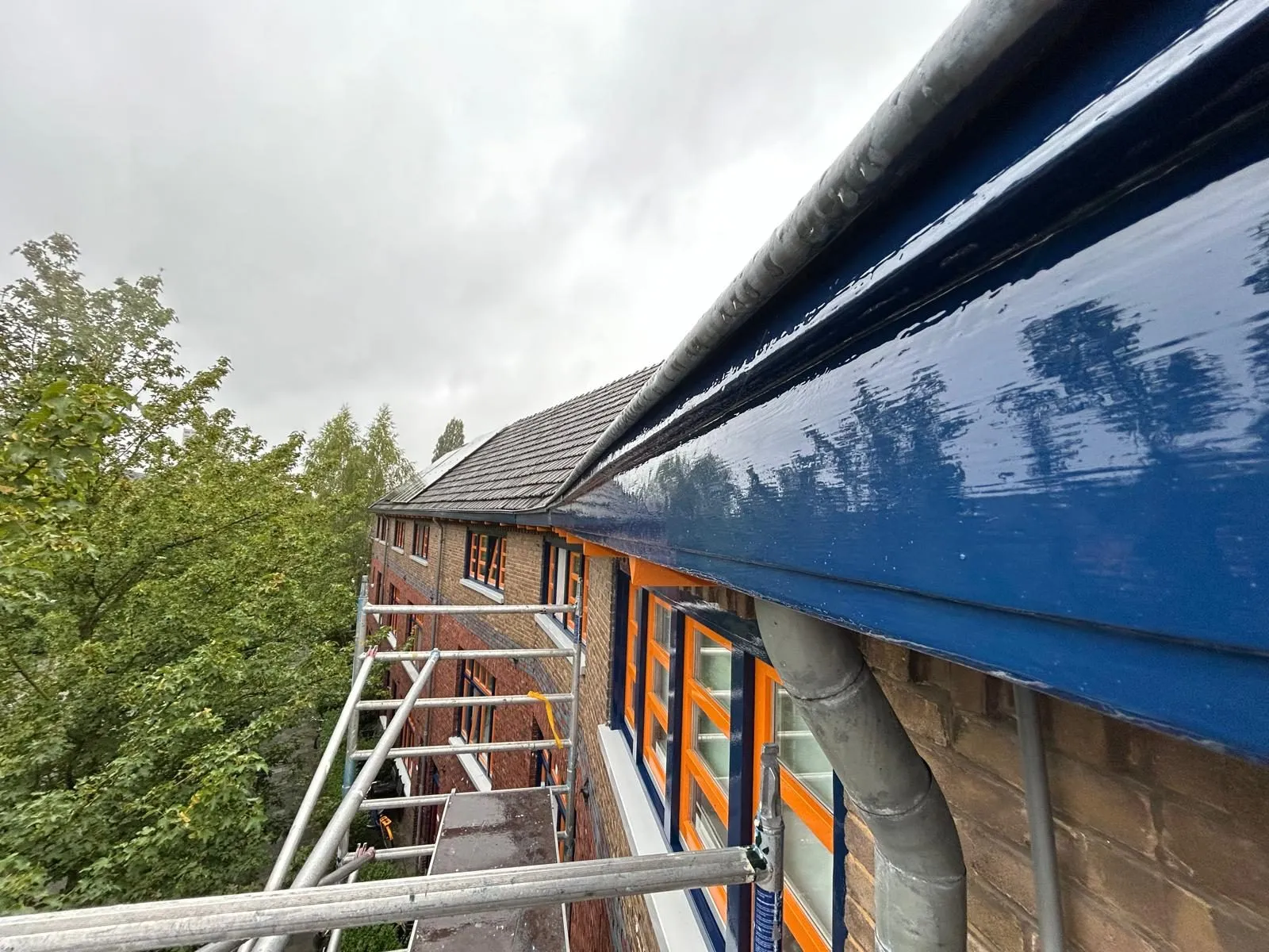 Glanzend donkerblauw geschilderde dakgoot met oranje accent