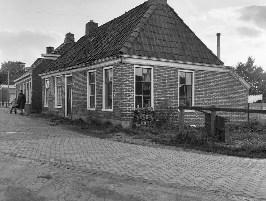 Oude zwart-witfoto van hetzelfde landelijke pand aan een kinderkopjesweg