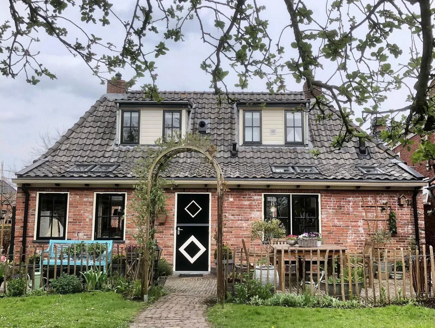 Landelijk pand met rozenboog, ruitmotieven op de deur en zesruitvensters