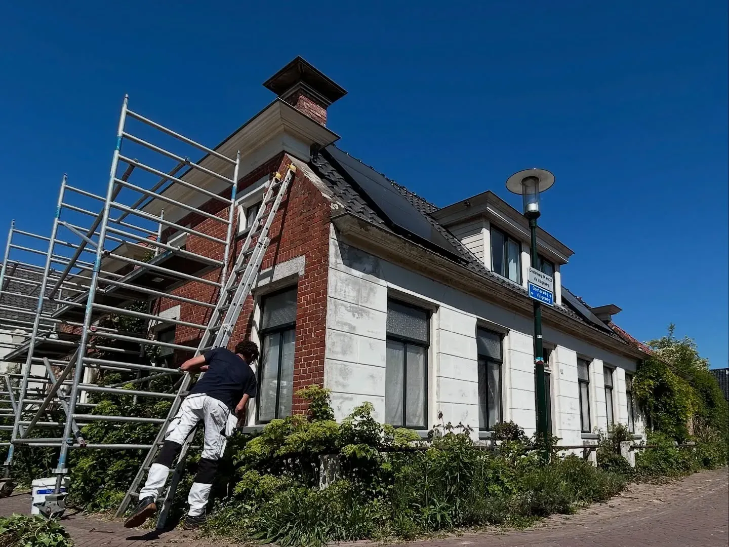 Schilder op een ladder tegen de zijgevel van de voormalige bakkerij