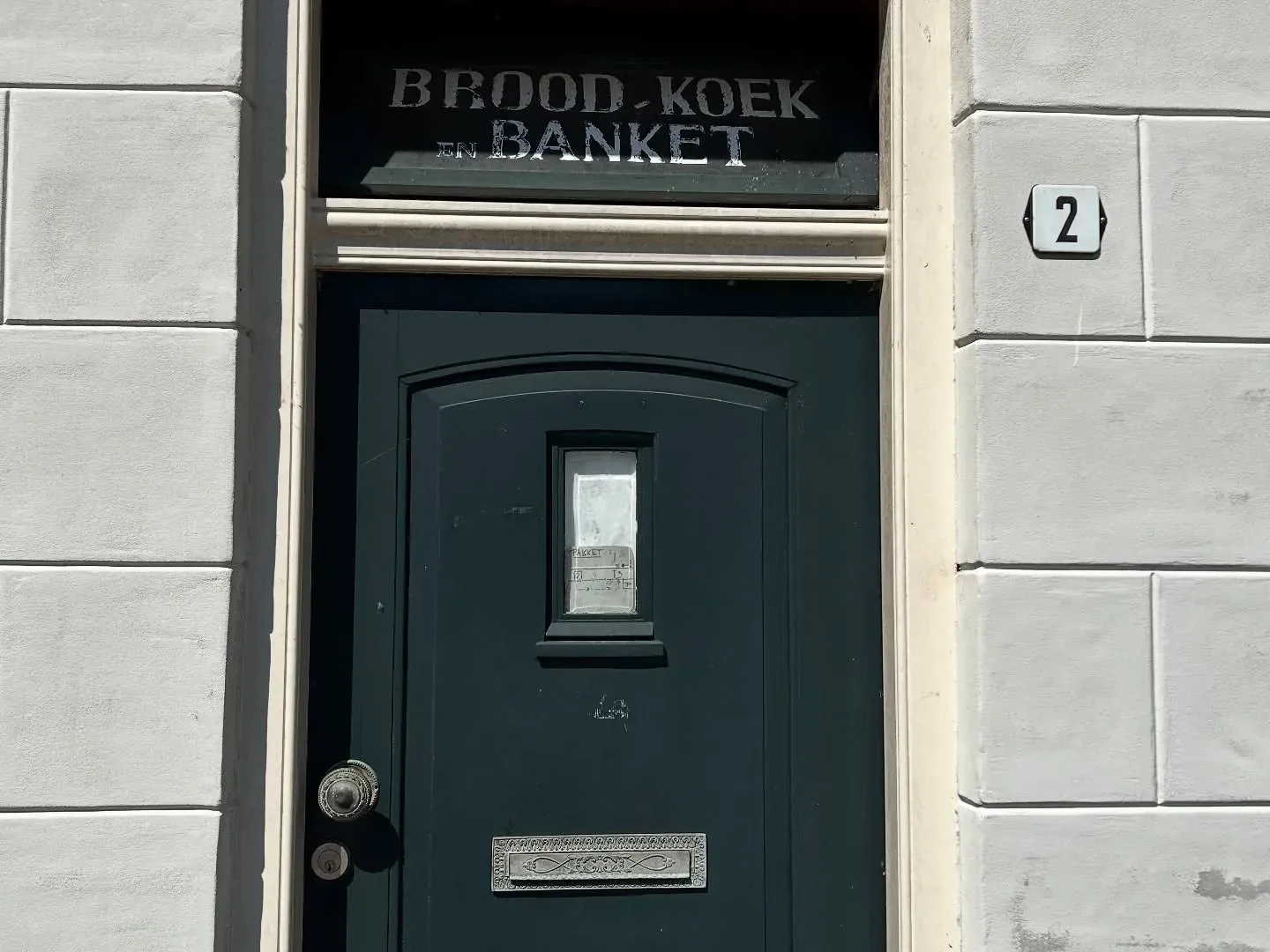 Donkergroene voordeur onder het gevelopschrift BROOD KOEK EN BANKET