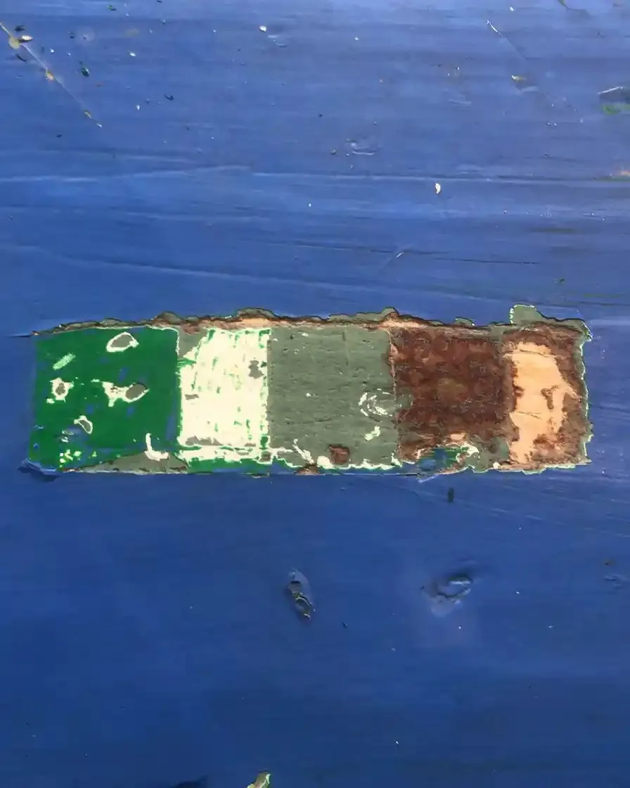Blootgelegde verflagen op een blauw geschilderd kozijn