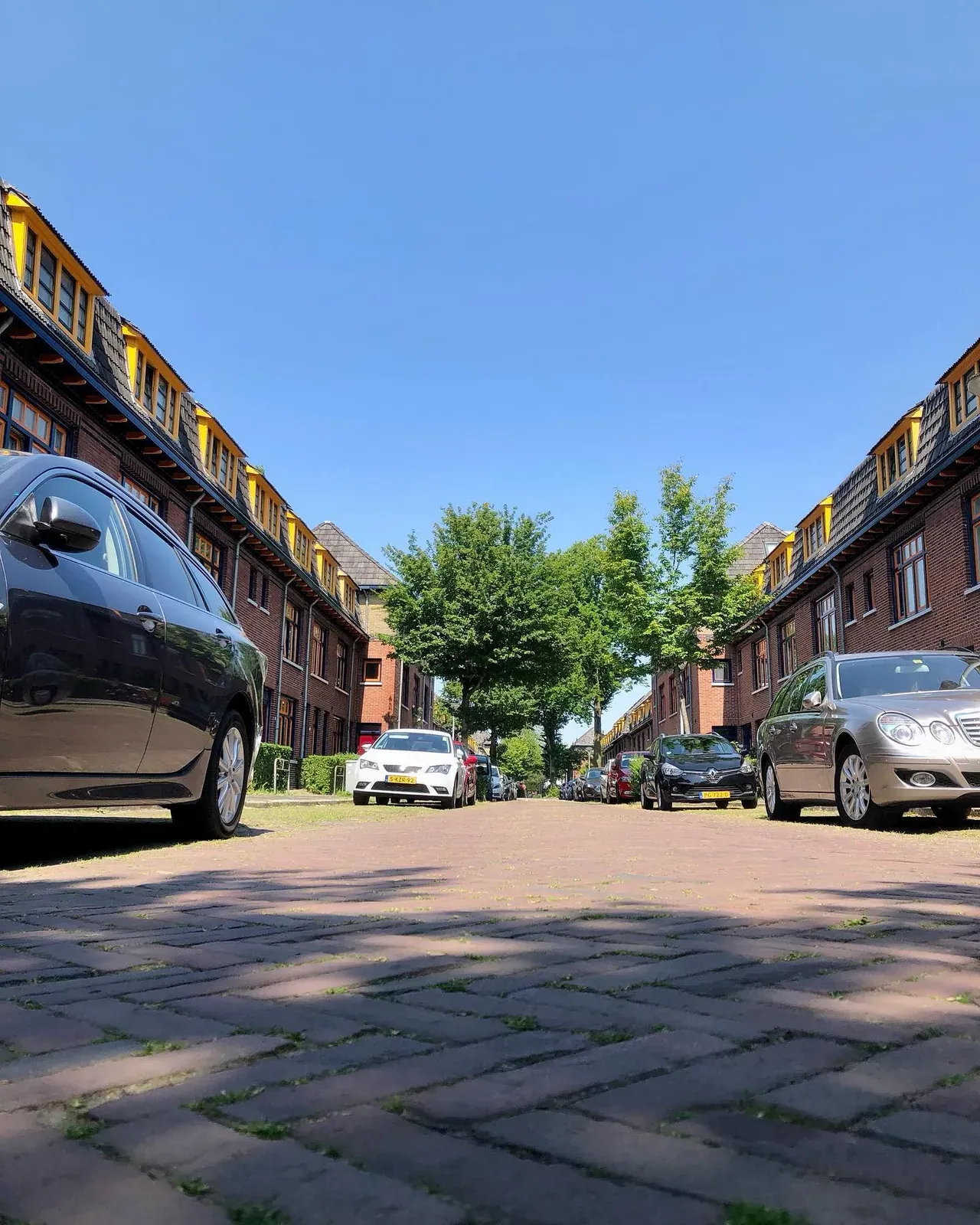 Straat met jaren-dertig woningen en gele kozijnen onder een blauwe lucht