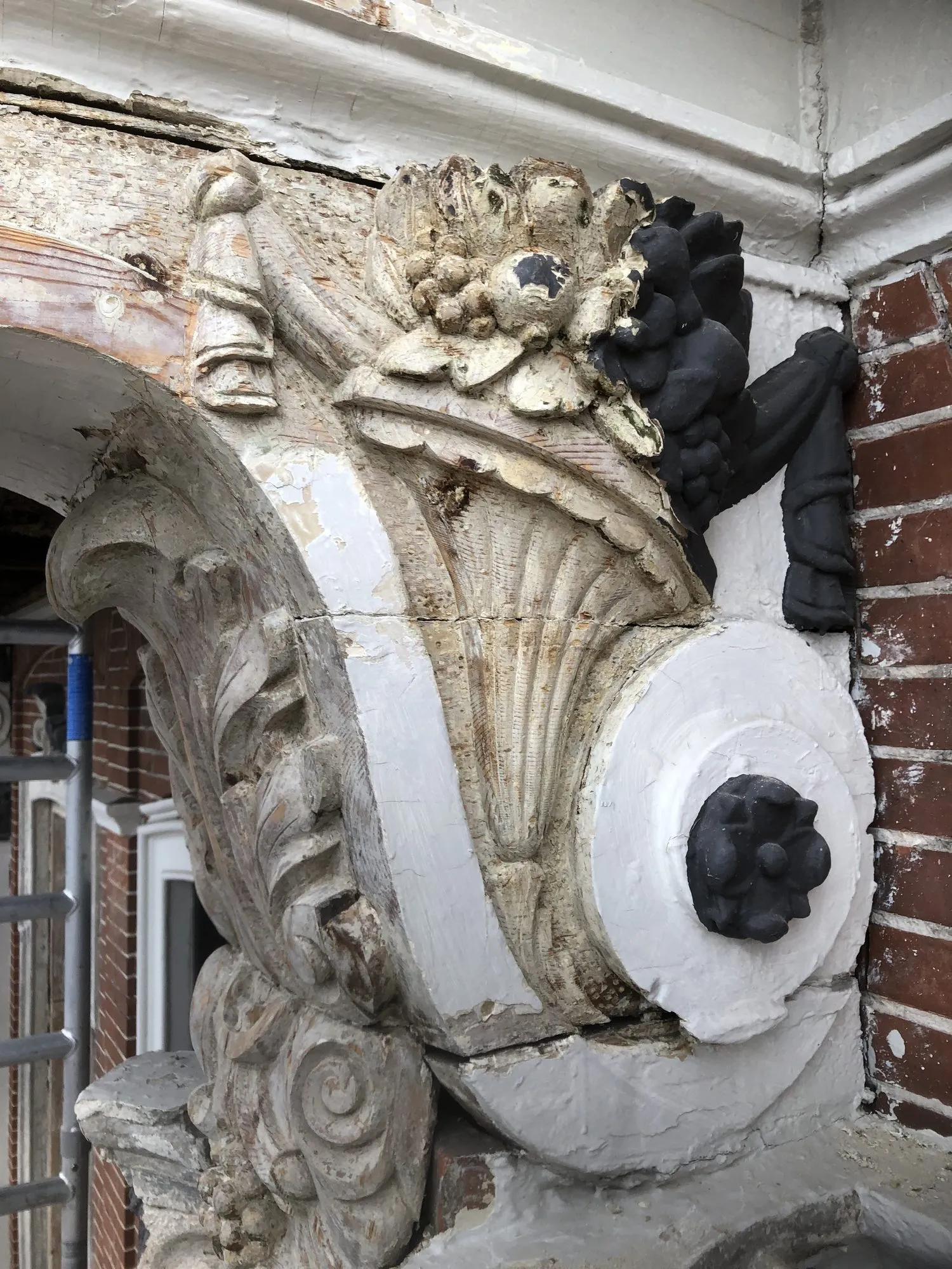 Gevelornament boven een deur tijdens de restauratie, deels gereinigd en deels nog in oude verf