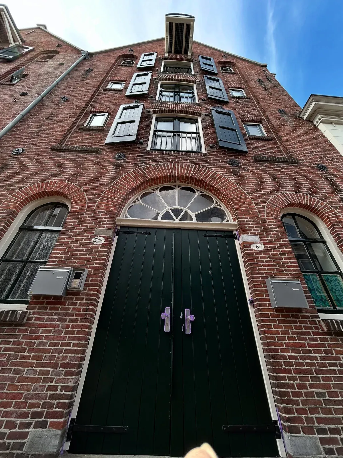 Het pakhuis van onderaf gezien, met de luiken en de zwarte deuren