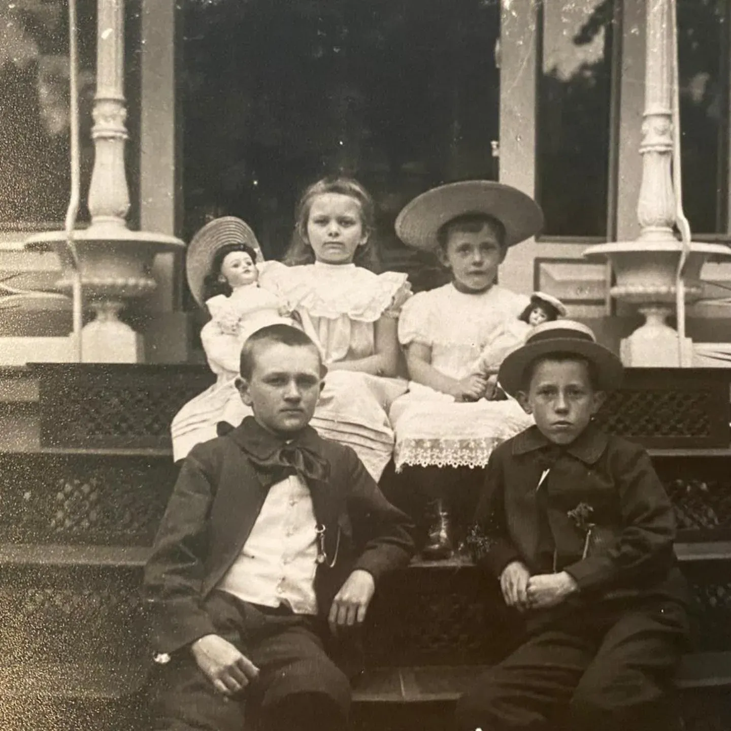 Oude zwart-witfoto van vier kinderen op de veranda van het pand