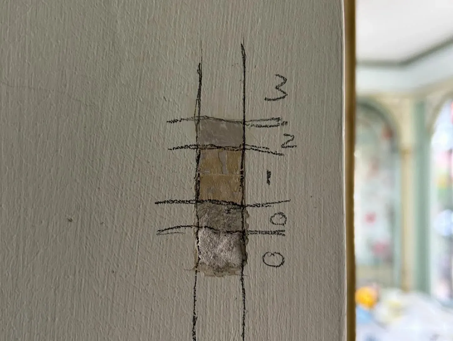 Kleurentrap op een wand: een raster van uitgeslepen vlakjes met genummerde verflagen