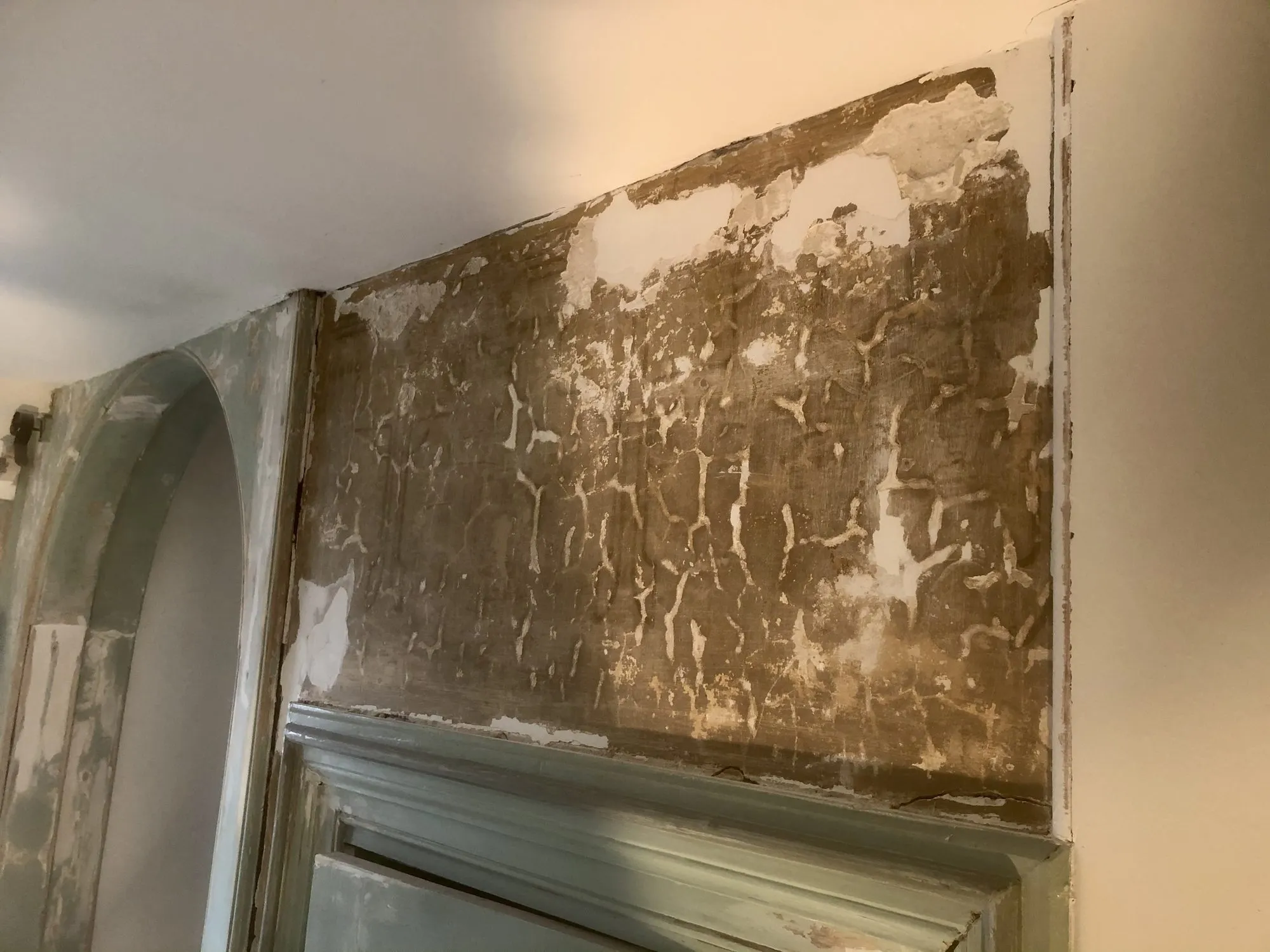 Oude verf- en behanglagen die op een wand zijn blootgelegd