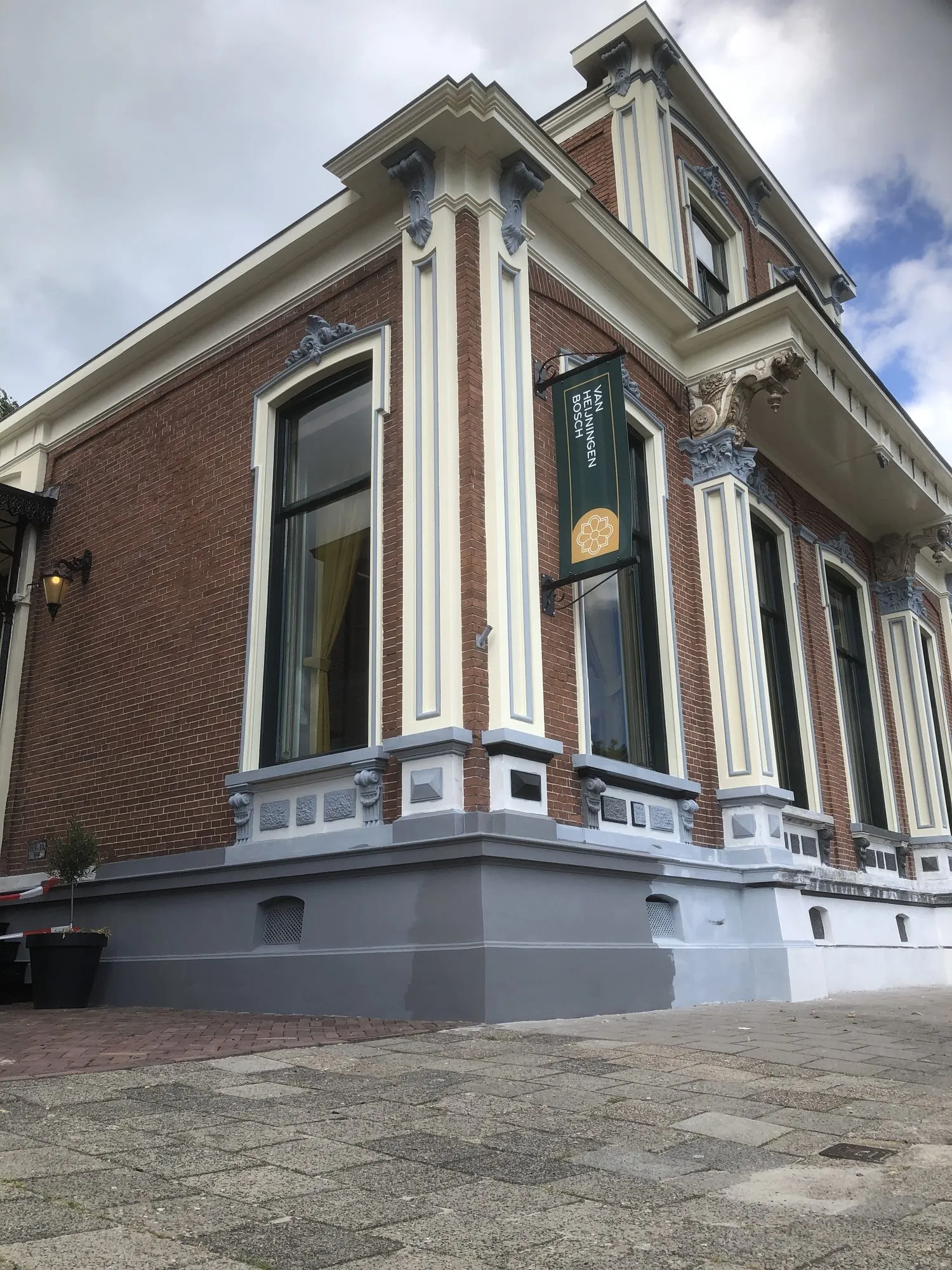 Hoek van een herenhuis met pas geschilderde pilasters in crème en een grijze plint