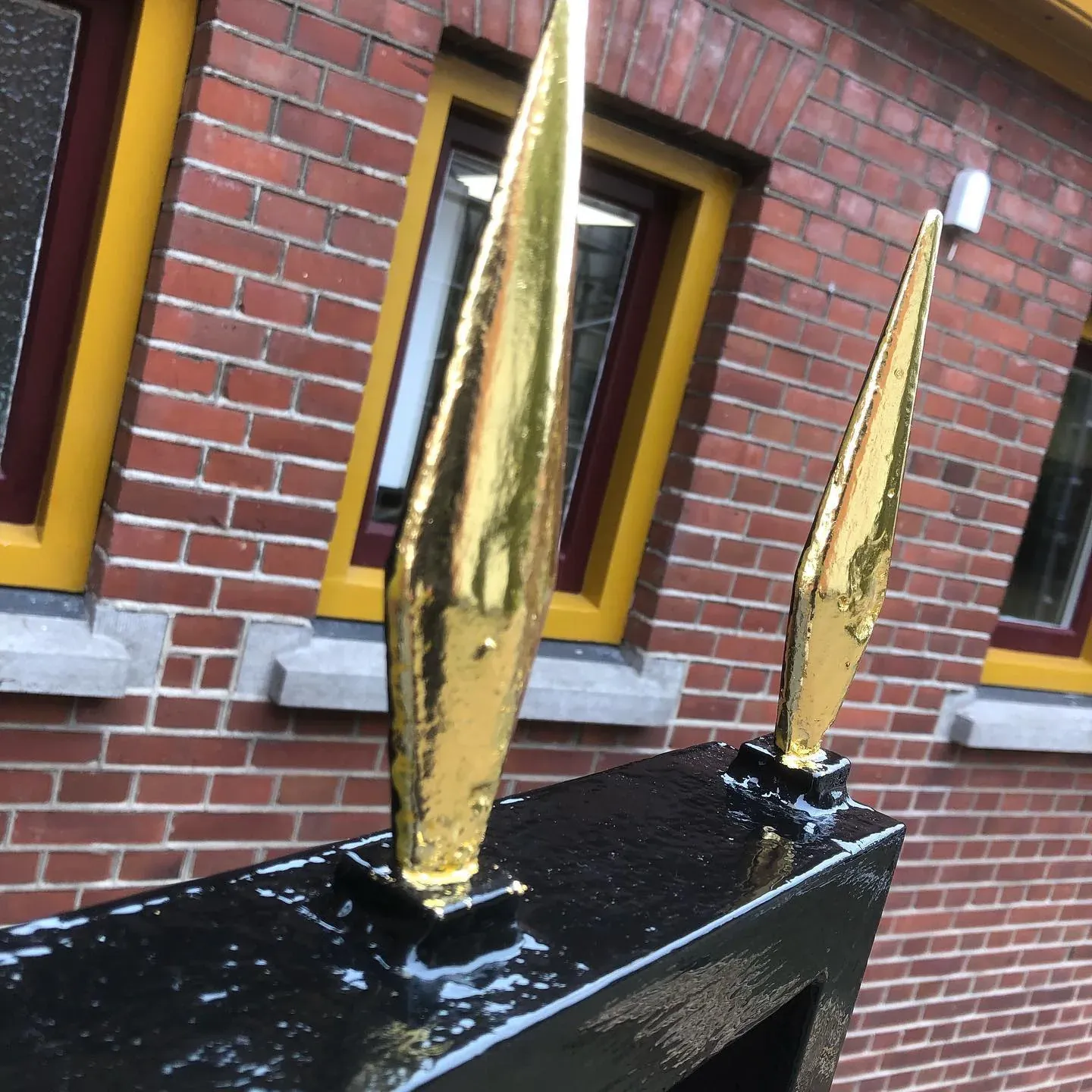 Twee met bladgoud verguldde speerpunten op een zwart hekwerk