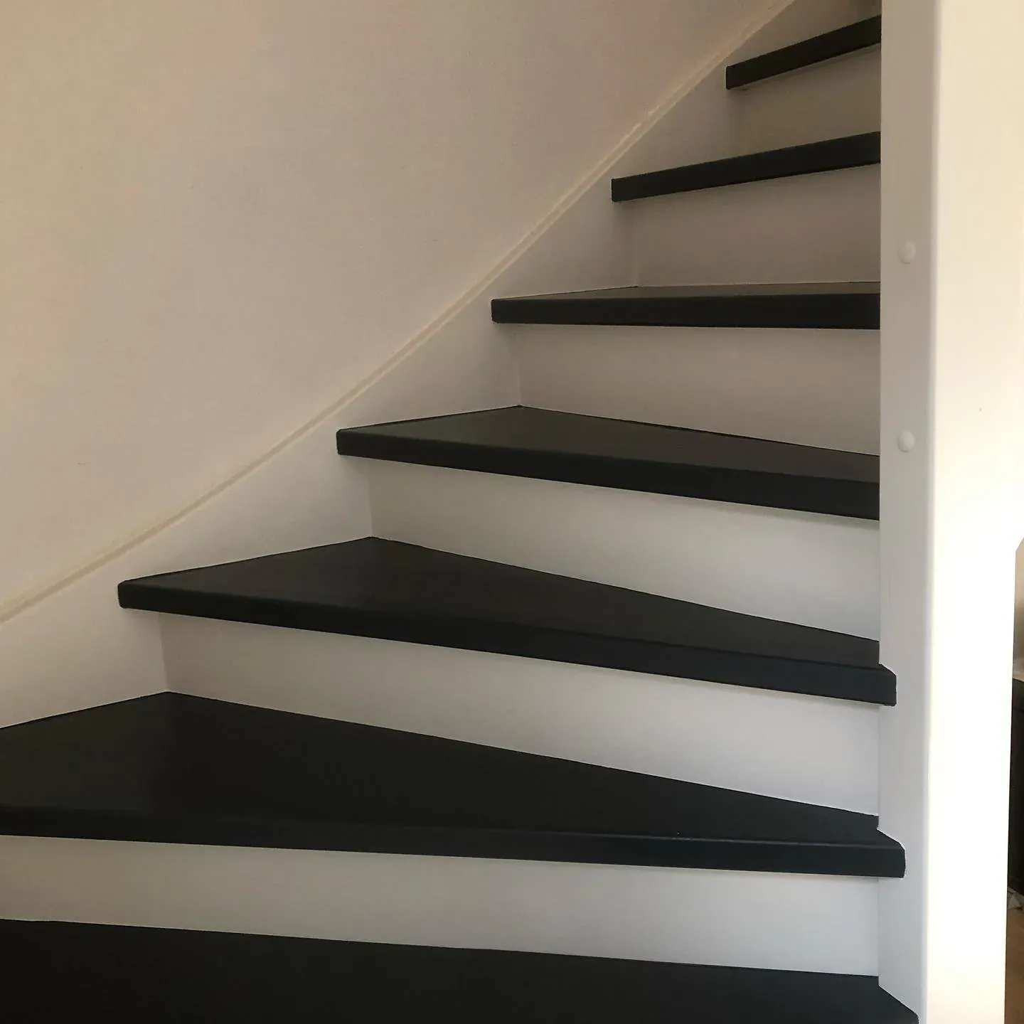 Trap met zwarte treden tegen een witte wand